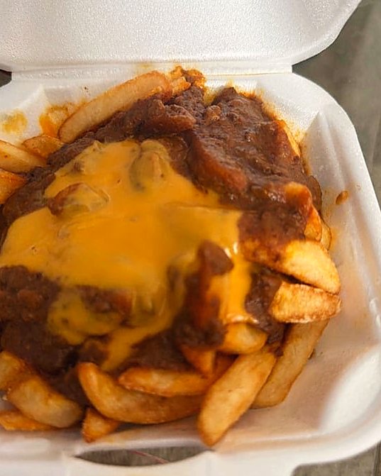 Chili cheese fries with melted American cheese in a takeout container.