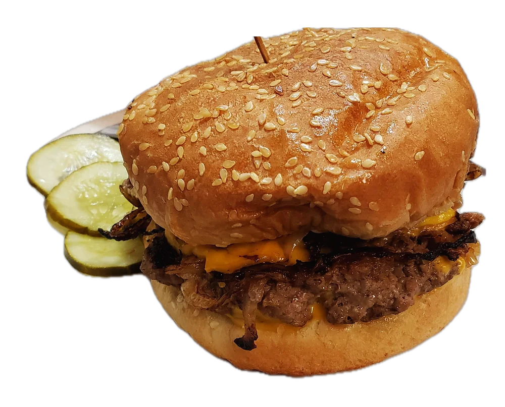 A Geneva's cheeseburger with grilled onions and melted American cheese on a sesame bun, with pickle slices beside it.