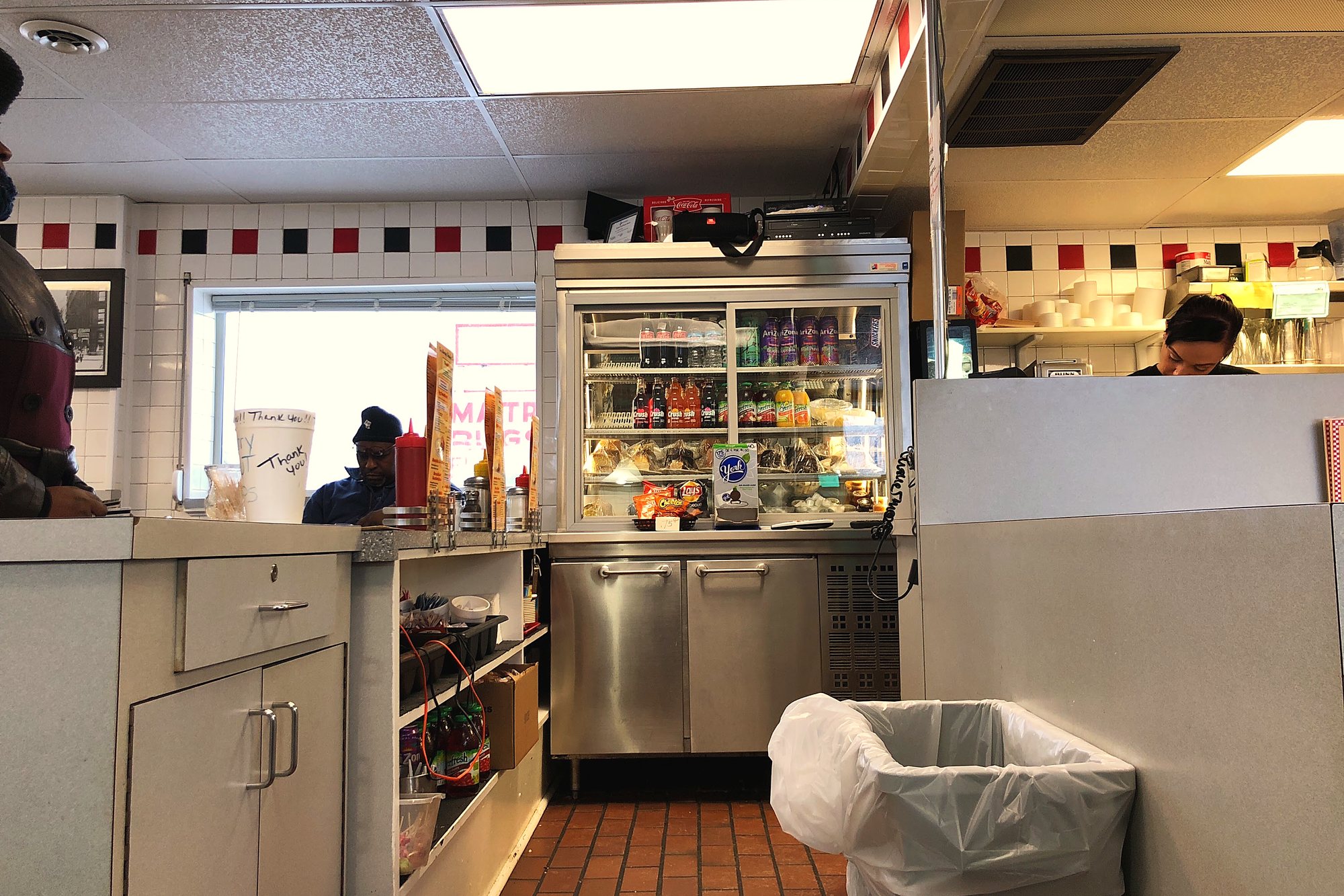 The counter at Geneva's, with the drinks cooler and the kitchen open behind it.